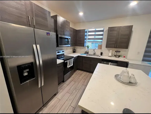 a kitchen with stainless steel appliances granite countertop a sink refrigerator and microwave