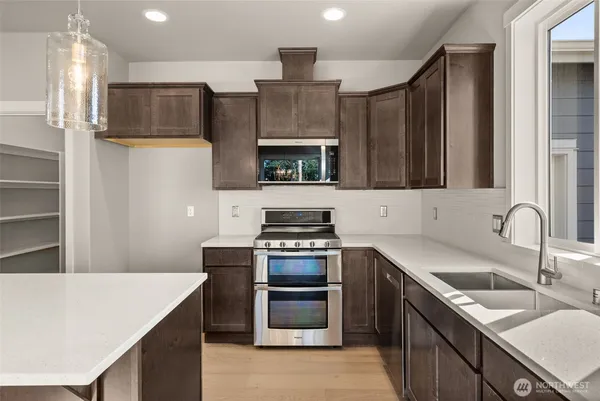 a kitchen with kitchen island a sink dishwasher a stove and a refrigerator with wooden floor