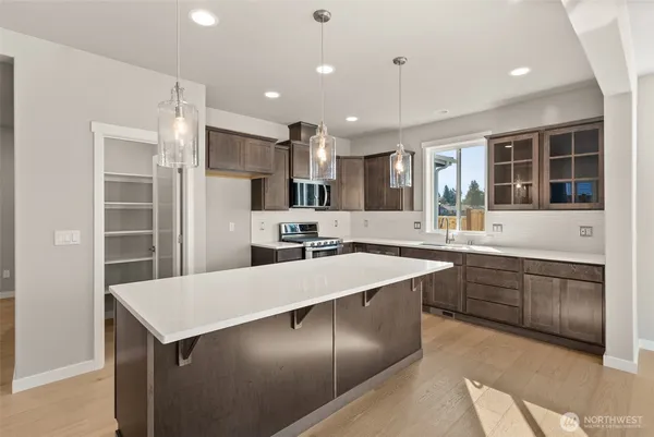 a kitchen with stainless steel appliances kitchen island granite countertop a sink a stove a refrigerator and chairs