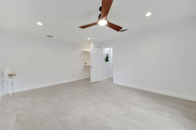 an empty room with ceiling fan and window