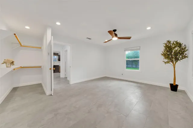 an empty room with windows and ceiling fan