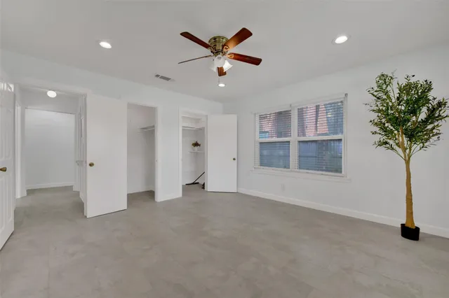 a view of an empty room with a ceiling fan and window