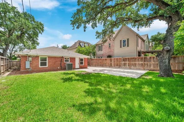 a view of a house with a yard and a large tree