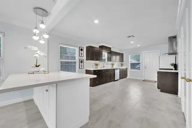 a large white kitchen with a stove a sink a kitchen island with wooden cabinets and floor