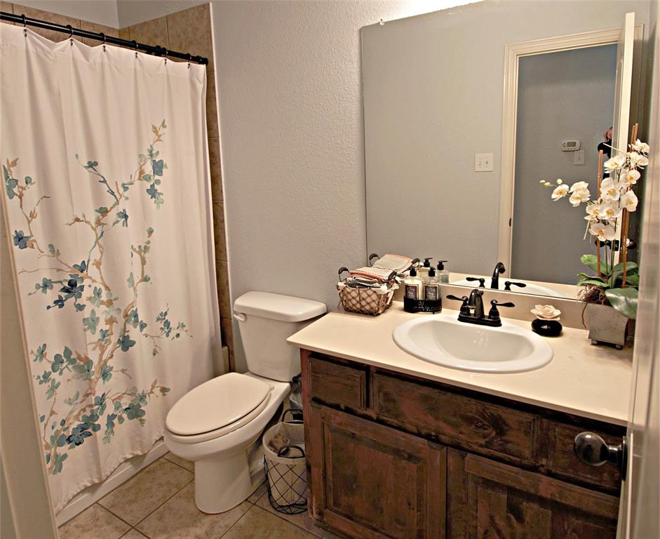 3702 Dogwood Road Melissa, TX 75454 - Photo 11 of 24 a bathroom with a sink a toilet and shower curtain