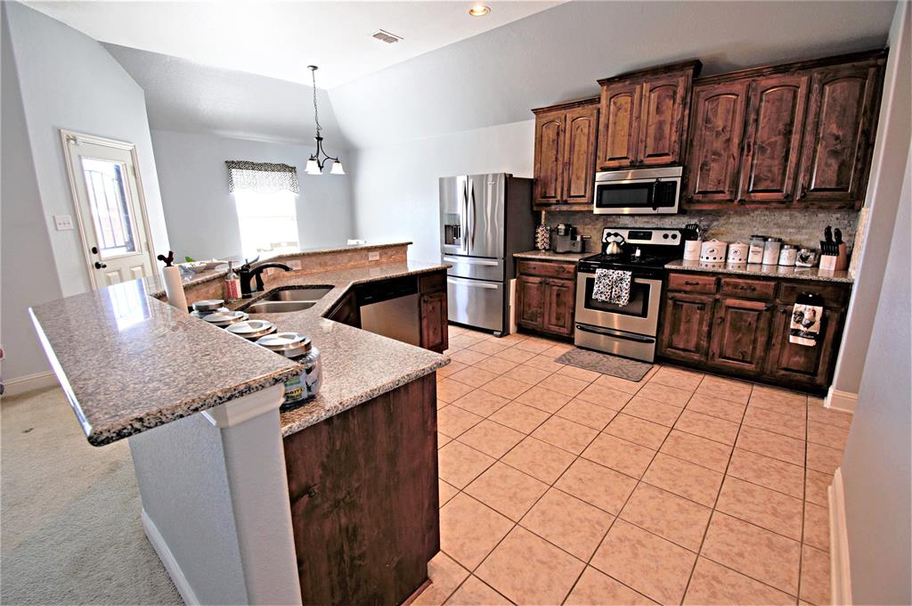 3702 Dogwood Road Melissa, TX 75454 - Photo 7 of 24 a kitchen with stainless steel appliances granite countertop a sink stove and refrigerator