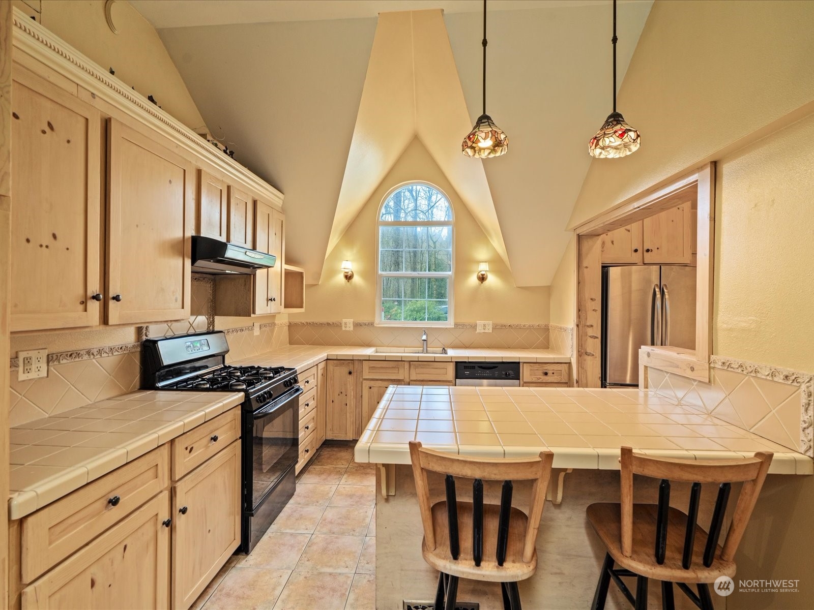 16446 Southeast Jones Road Renton, WA 98058 - Photo 13 of 40 a kitchen with stainless steel appliances a stove a sink dishwasher and a dining table with wooden floor