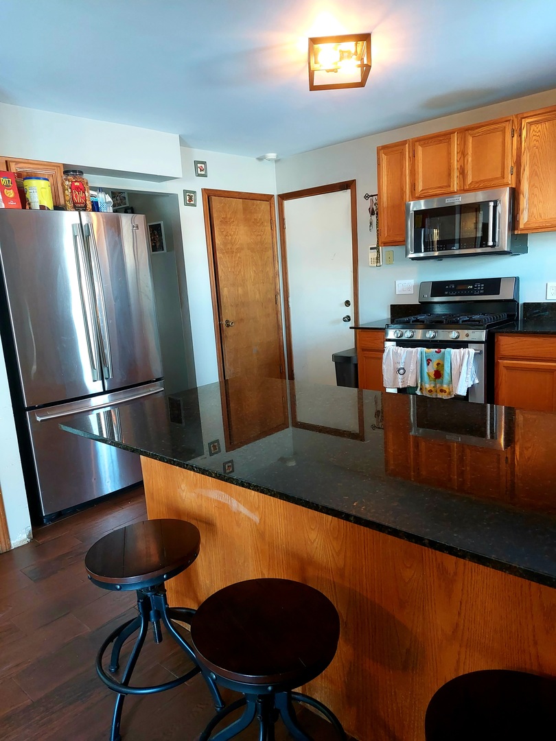 44-w046 Rohrsen Road Hampshire, IL 60140 - Photo 8 of 34 a kitchen with stainless steel appliances granite countertop a refrigerator a stove and a sink with wooden floor