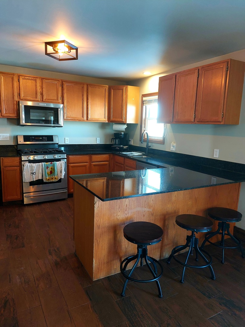 44-w046 Rohrsen Road Hampshire, IL 60140 - Photo 9 of 34 a kitchen with stainless steel appliances wooden cabinets a stove a sink and a microwave