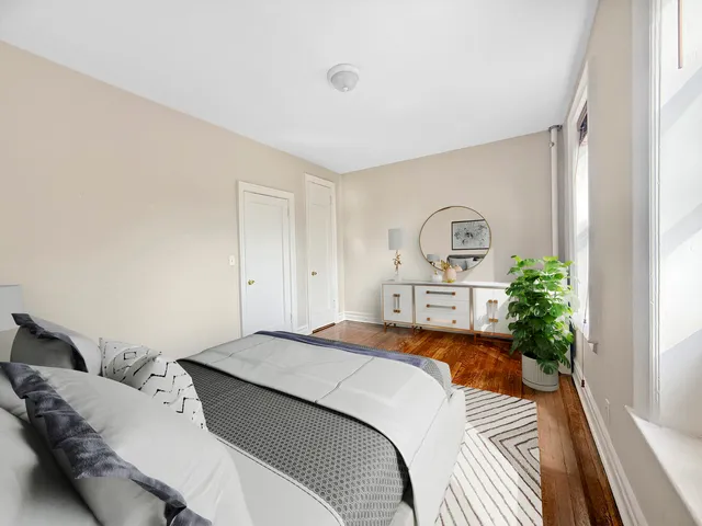 a spacious bedroom with a large bed a potted plant and a window