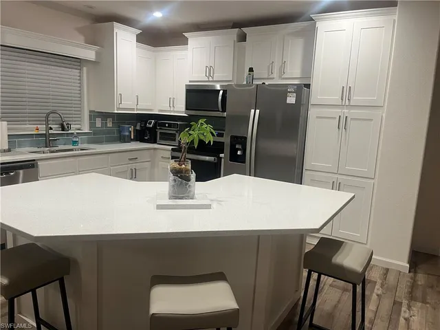 a kitchen with stainless steel appliances a dining table chairs and refrigerator