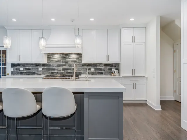 a kitchen with stainless steel appliances granite countertop a stove a sink a refrigerator and white cabinets with wooden floor