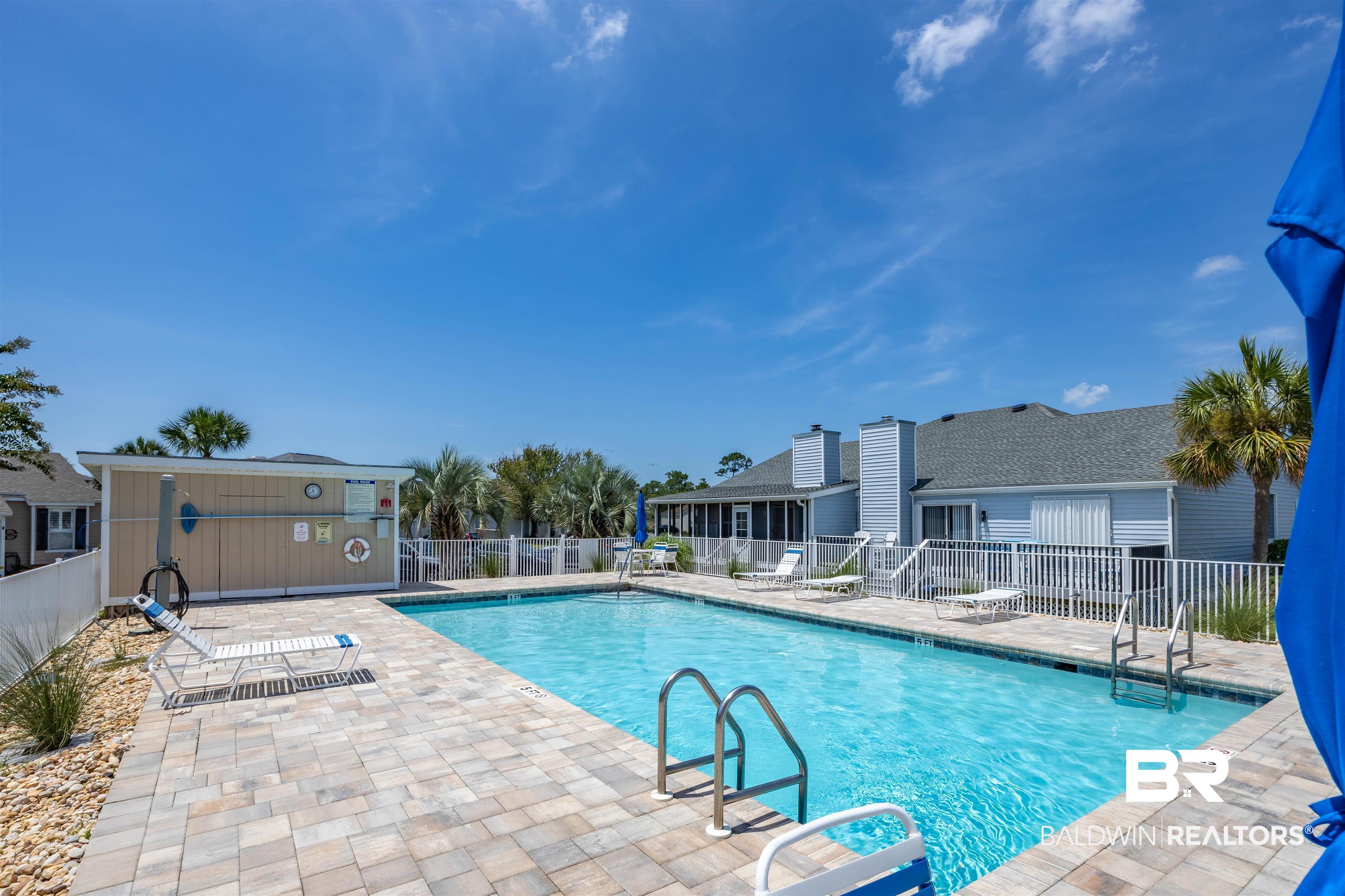 3200 Loop Road, Unit 96 Orange Beach, AL 36561 - Photo 45 of 49 Outdoor swimming pool featuring a paver deck, white perimeter fencing, and an adjacent cabana building