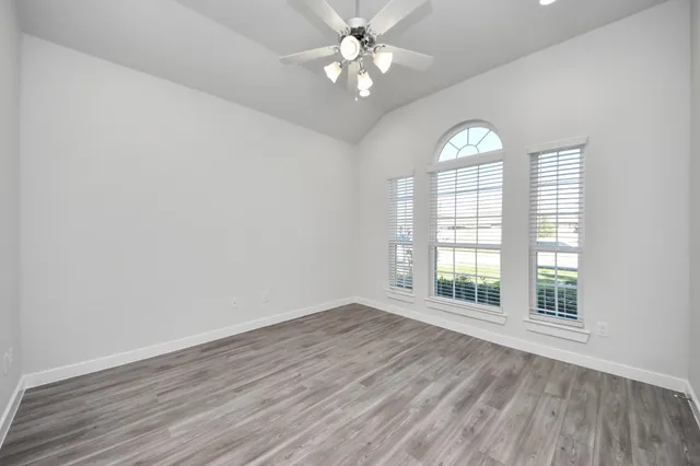 an empty room with wooden floor and windows