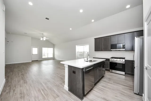 a kitchen with stainless steel appliances granite countertop a sink a stove top oven a wooden floors