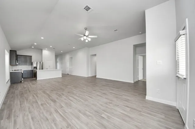 a view of kitchen and empty room with wooden floor