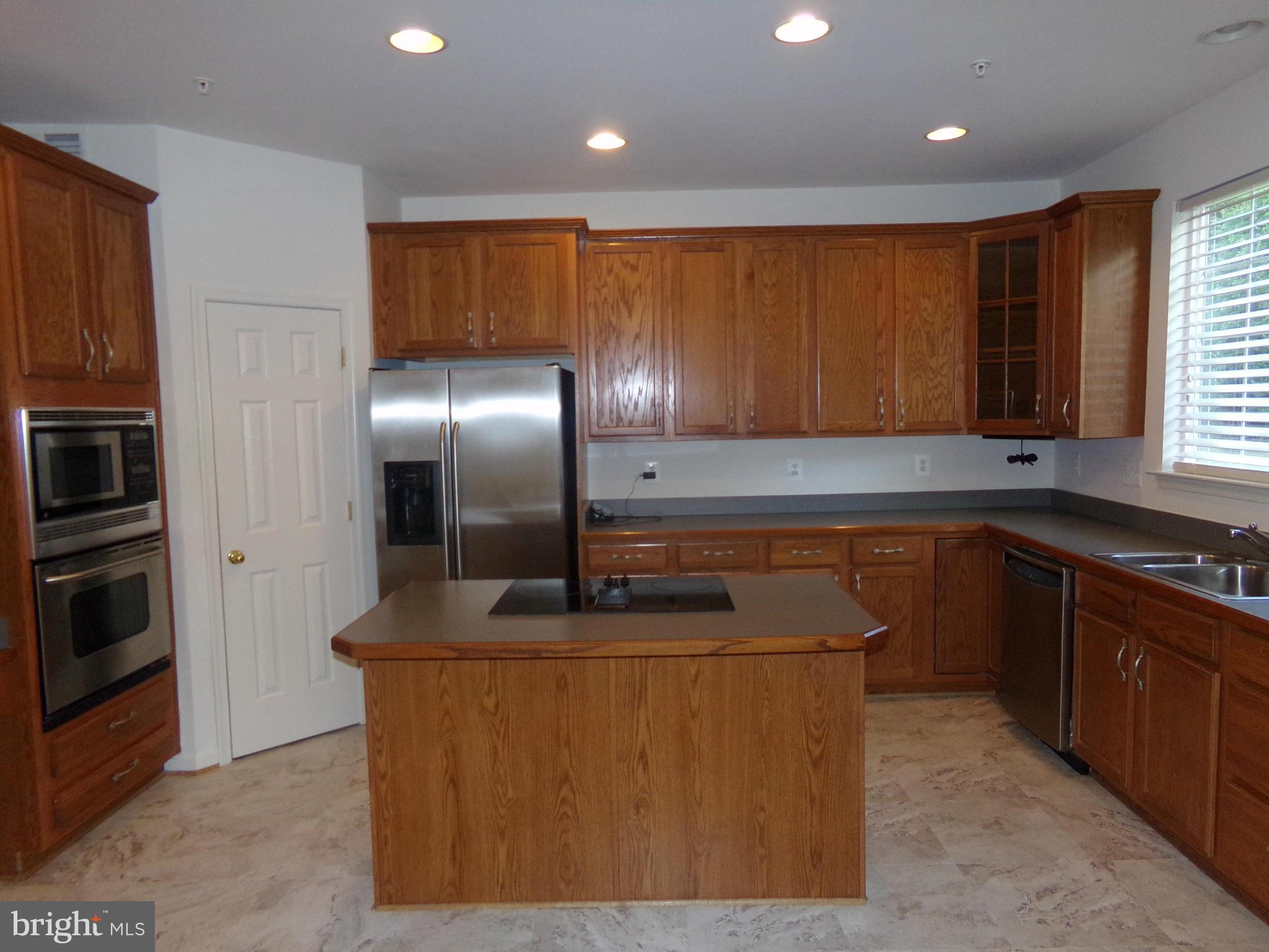 9834 Farm Pond Road Laurel, MD 20708 - Photo 14 of 30 a kitchen with kitchen island granite countertop wooden cabinets and stainless steel appliances