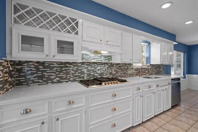 a kitchen with white cabinets and sink