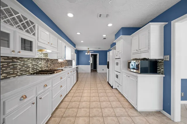 a large white kitchen with stainless steel appliances granite countertop a stove a sink and a refrigerator