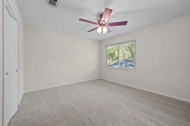 an empty room with window and ceiling fan