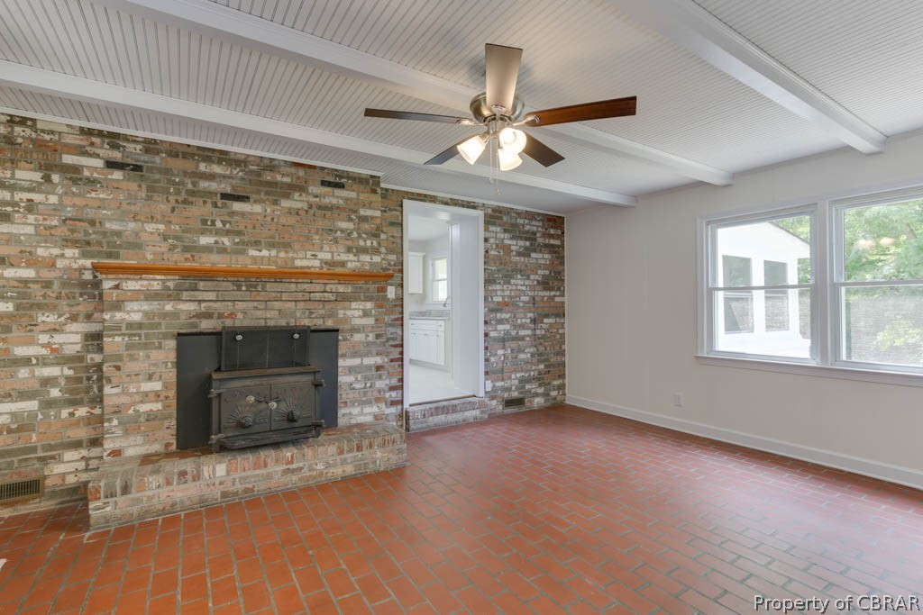400 Showalter Road Yorktown, VA 23692 - Photo 22 of 49 Unfurnished living room featuring a wood stove, a fireplace, beam ceiling, brick wall, and ceiling fan