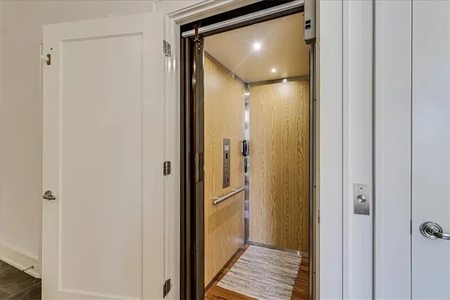 a view of a hallway with wooden floor and a bathroom