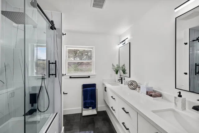 a bathroom with a double vanity sink a mirror a window and a shower