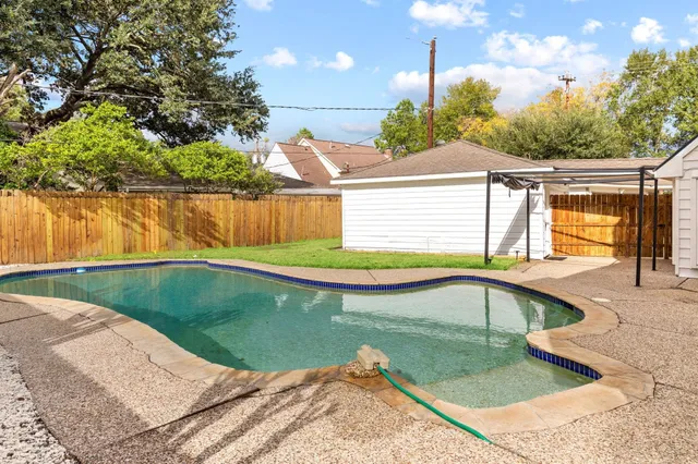 a view of a swimming pool with a yard and plants
