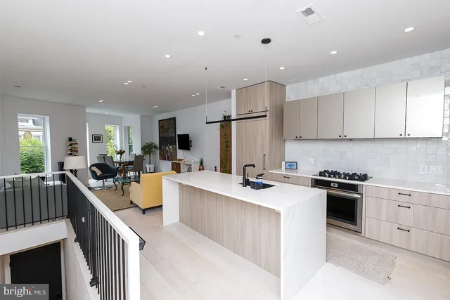 a view of a kitchen with kitchen island a stove a sink a refrigerator and cabinets