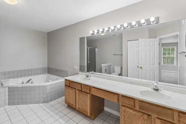 a spacious bathroom with a double vanity sink mirror and bathtub