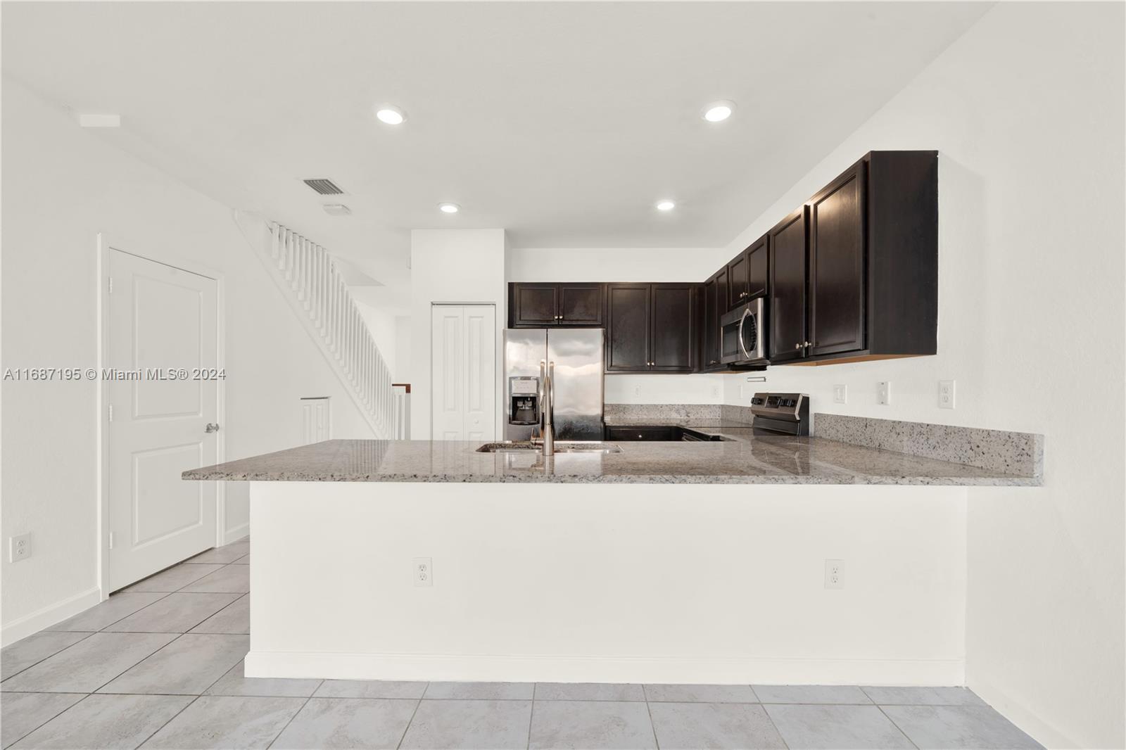 11343 Southwest 250th Terrace, Unit 11343 Homestead, FL 33032 - Photo 11 of 37 a large kitchen with granite countertop a sink and a stove top oven with wooden floor