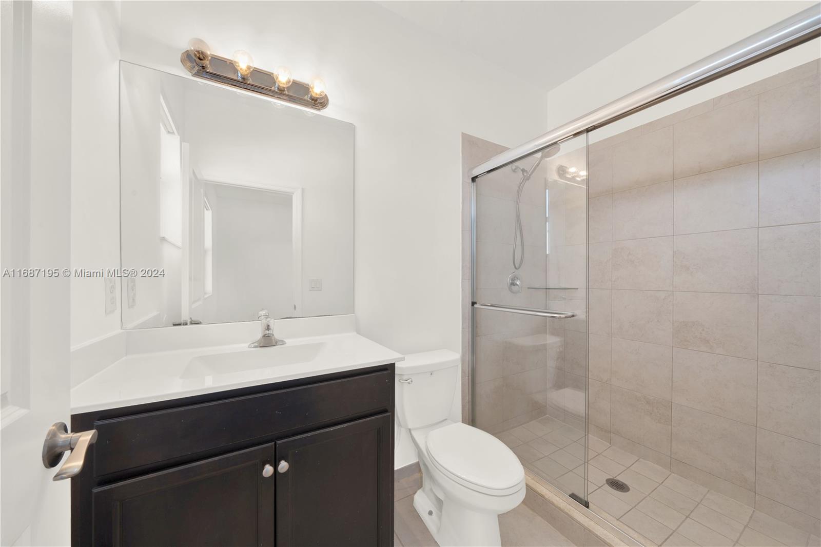 11343 Southwest 250th Terrace, Unit 11343 Homestead, FL 33032 - Photo 19 of 37 a bathroom with a sink a toilet a mirror and shower