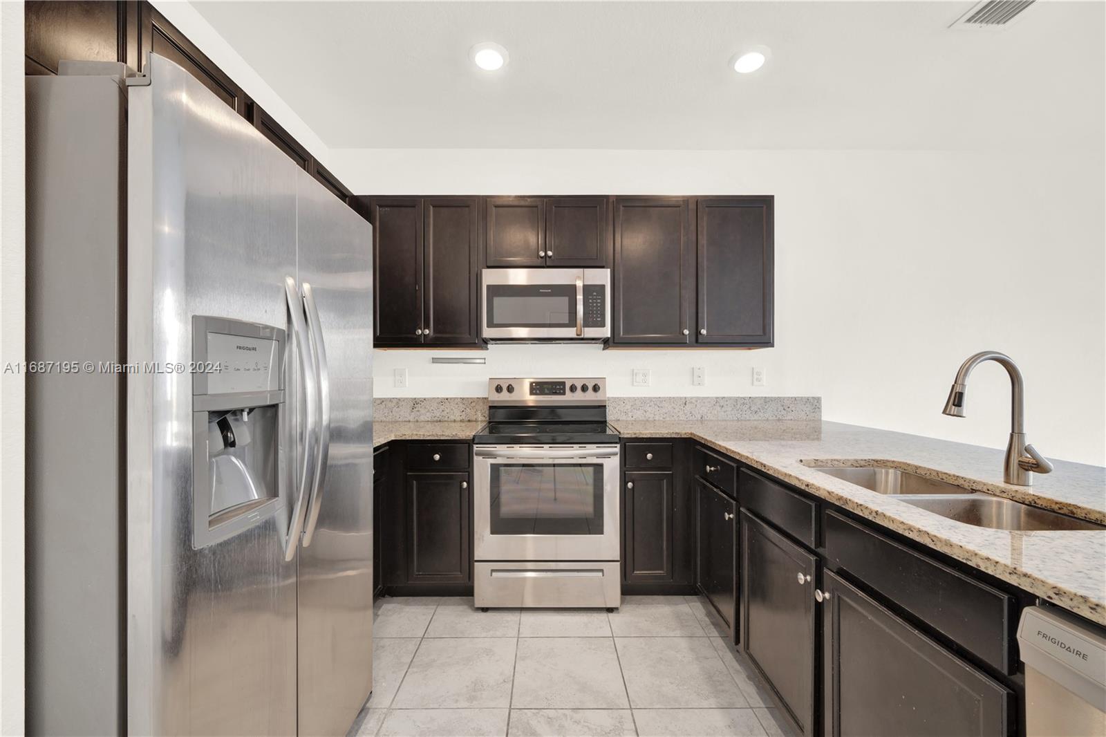 11343 Southwest 250th Terrace, Unit 11343 Homestead, FL 33032 - Photo 7 of 37 a kitchen with a sink and a stove top oven with wooden cabinets