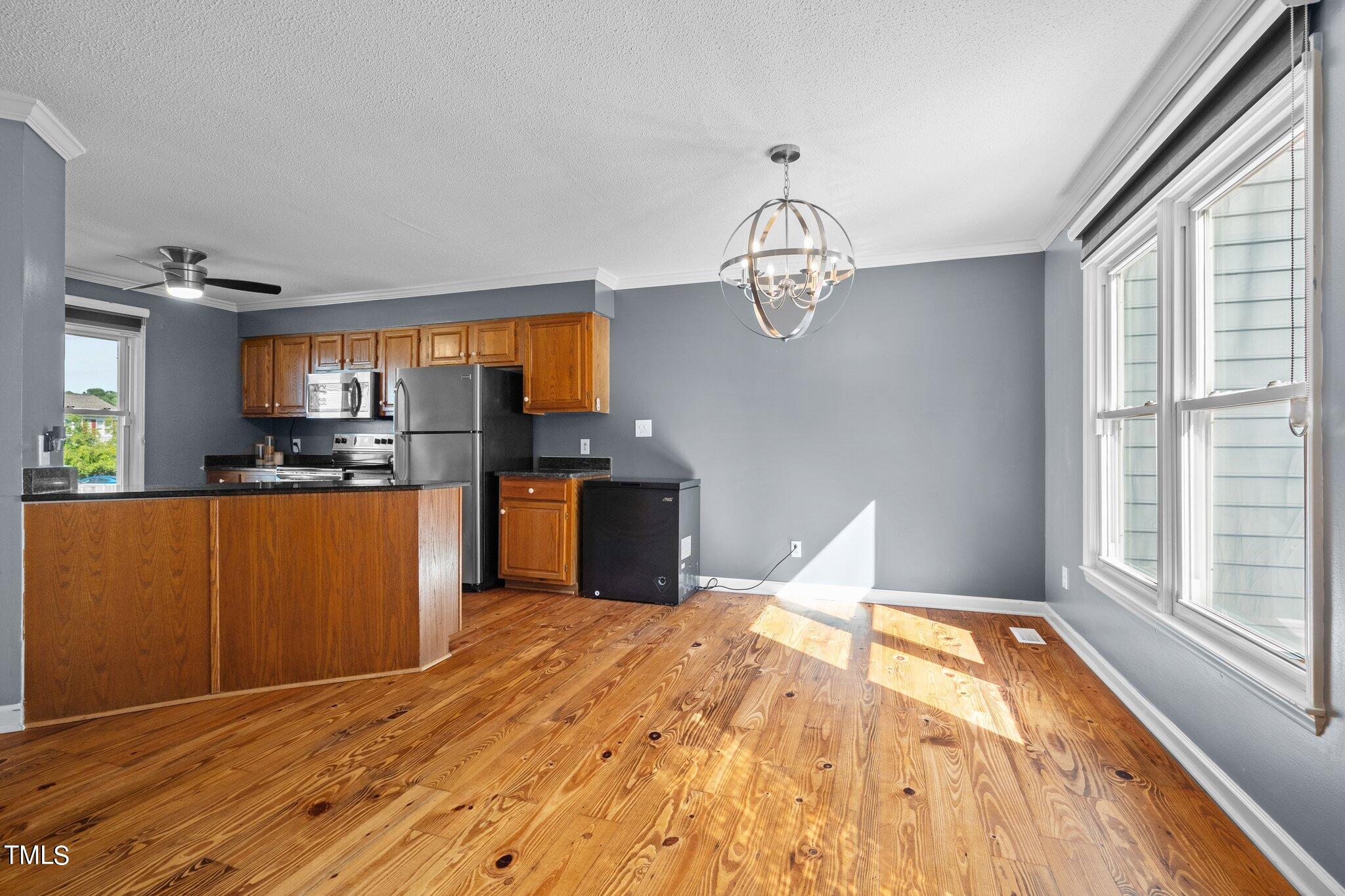 3520 Rawdon Drive Durham, NC 27713 - Photo 5 of 30 a kitchen with stainless steel appliances kitchen island granite countertop a refrigerator cabinets and wooden floor