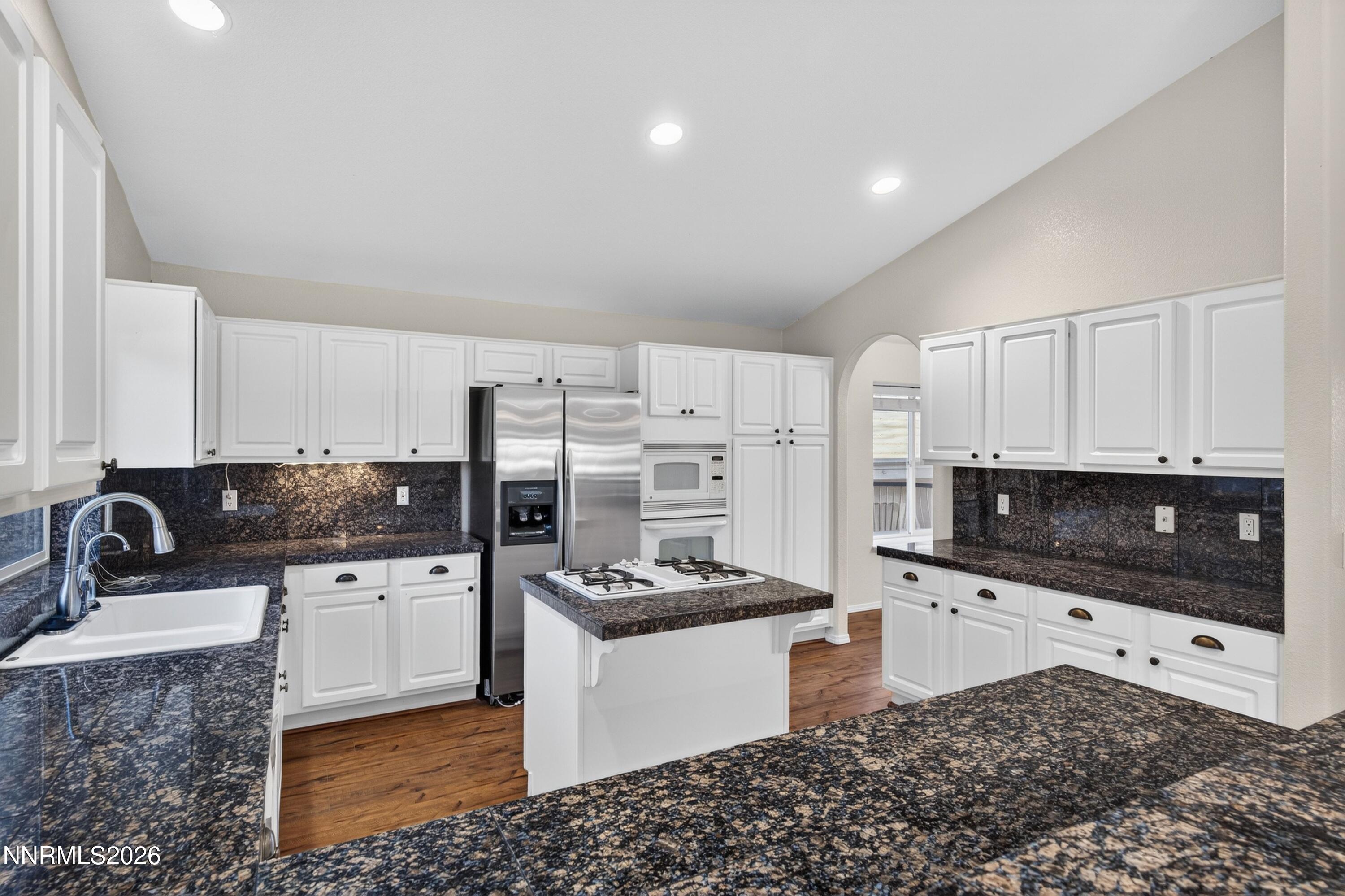 6279 Golden Meadow Road Reno, NV 89519 - Photo 13 of 57 a kitchen with stainless steel appliances kitchen island granite countertop a sink and white cabinets