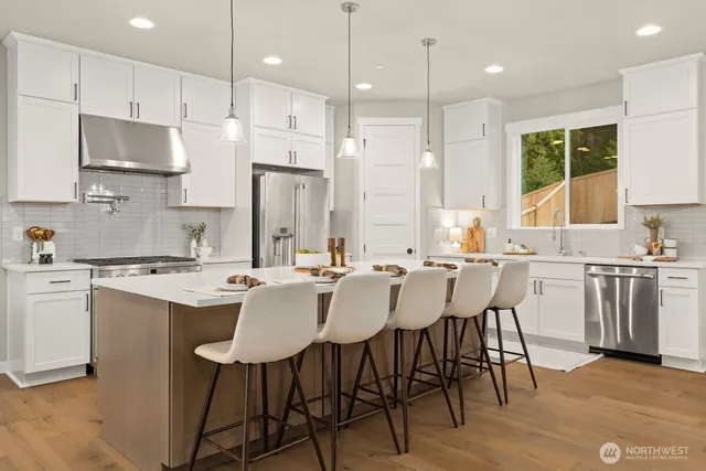 a kitchen with stainless steel appliances granite countertop a stove a sink a microwave a island with a dining table and chairs