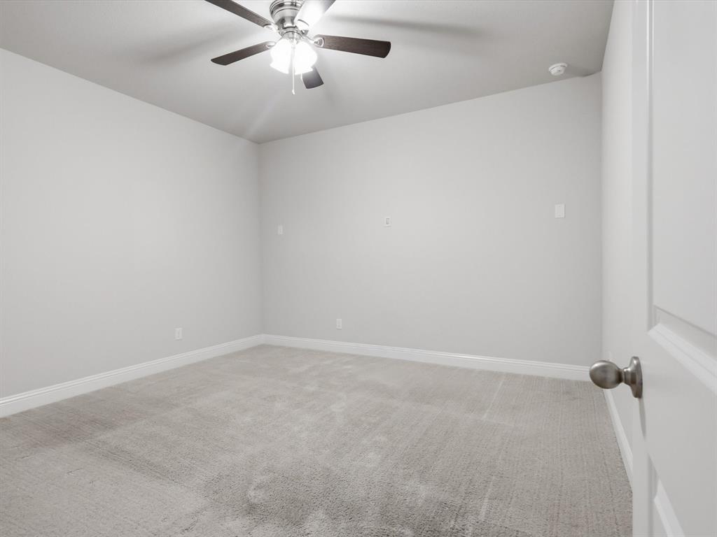 1601 Radecke Road Krum, TX 76249 - Photo 27 of 36 Neutral-toned room featuring a ceiling fan with integrated lighting, light gray wall paint, and gray carpet flooring