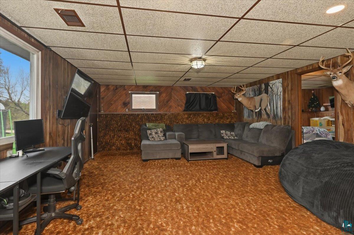 5190 County Road M Gordon, WI 54838 - Photo 14 of 31 Finished lower level space featuring wood paneling, textured ceiling tiles, and a large window providing natural light