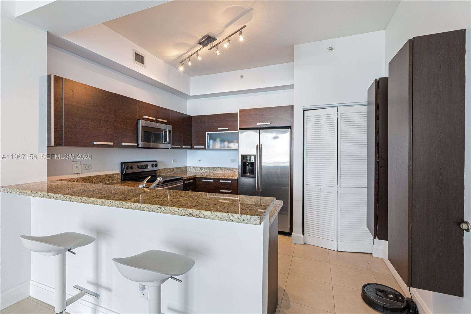 2525 Southwest 3rd Avenue, Unit 1708 Miami, FL 33129 - Photo 16 of 26 a kitchen with stainless steel appliances granite countertop a refrigerator a stove a sink dishwasher and white cabinets with wooden floor