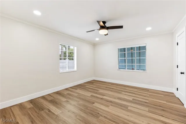 a view of empty room with wooden floor and fan