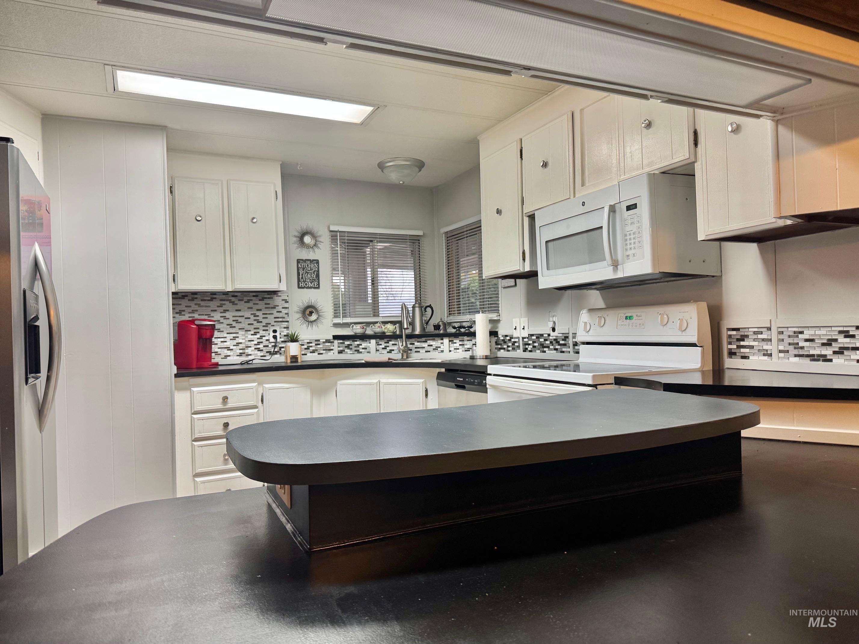 3181 West Alpine Street, Unit 22 Boise, ID 83705 - Photo 8 of 24 Kitchen with dark countertops, stainless steel appliances, white cabinetry, and tasteful backsplash