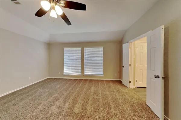 an empty room with chandelier fan and windows