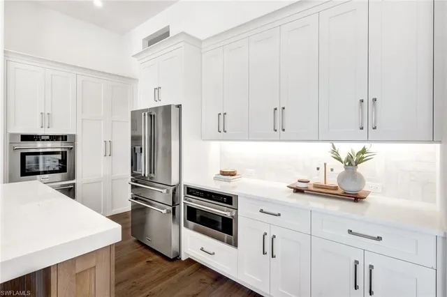 a kitchen with granite countertop white cabinets and stainless steel appliances