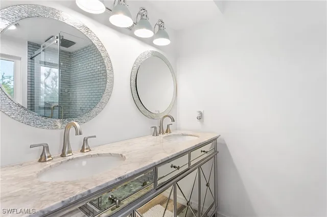 a bathroom with a granite countertop double vanity and a mirror