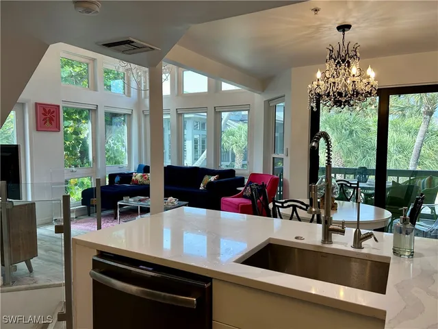 a view of a dining room with furniture a chandelier and large windows