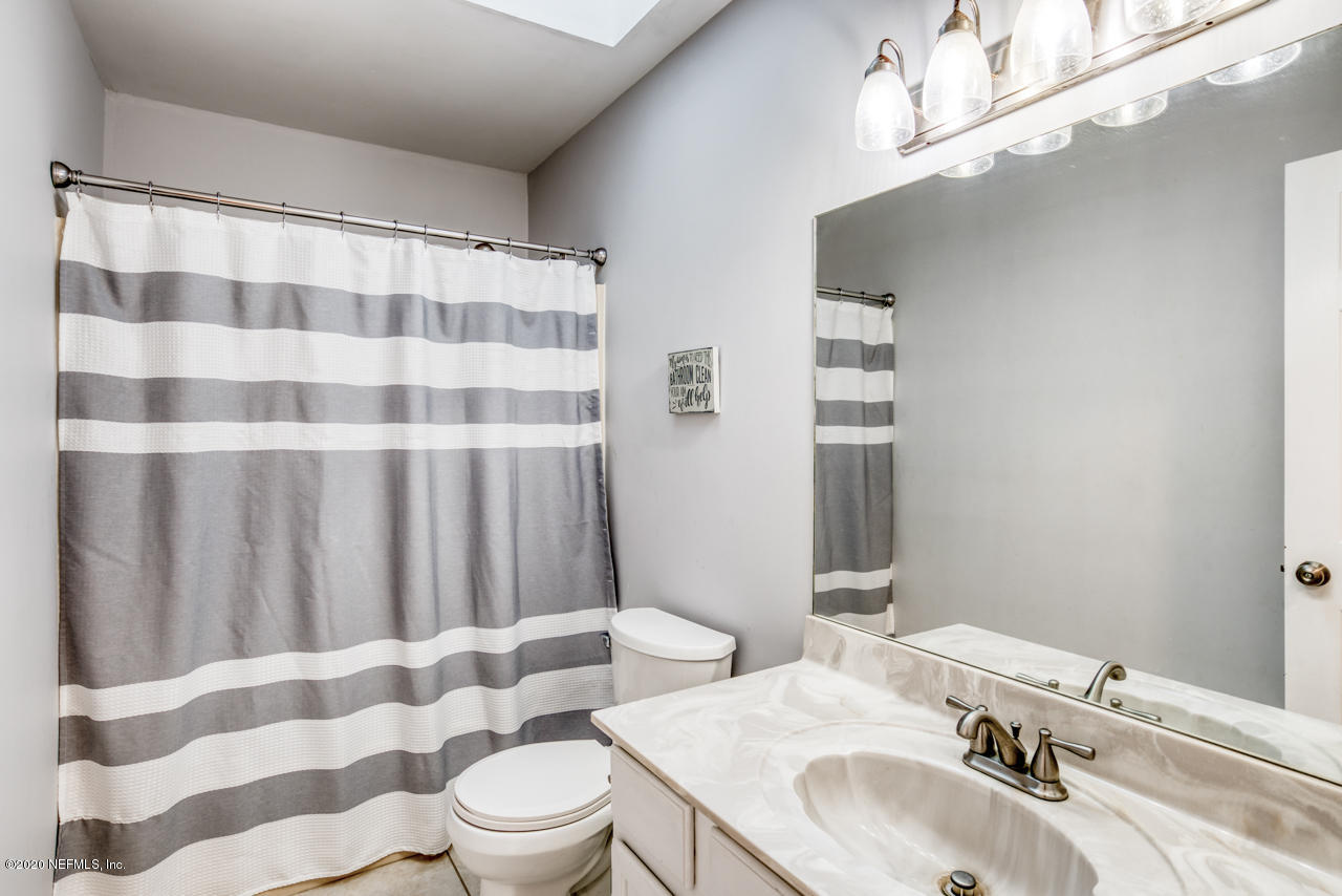332 Shamrock Road St. Augustine, FL 32086 - Photo 15 of 26 a bathroom with a sink a toilet a mirror and shower curtain