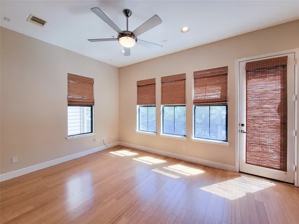 a view of an empty room with a window and wooden floor