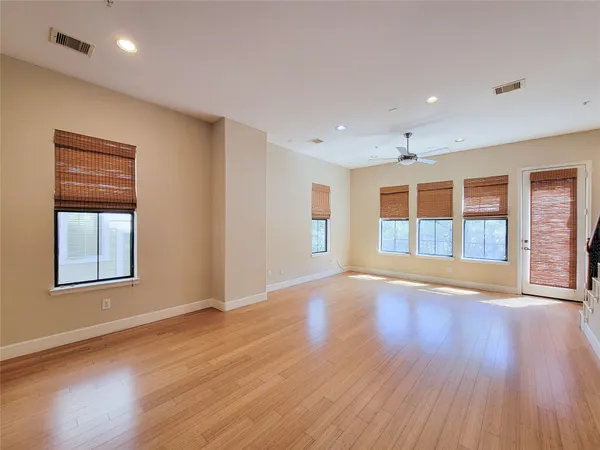 a view of an empty room with wooden floor and windows