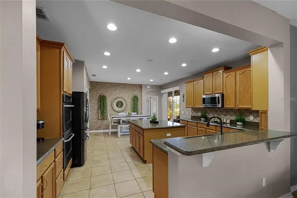 a kitchen with stainless steel appliances granite countertop a sink a stove and a refrigerator
