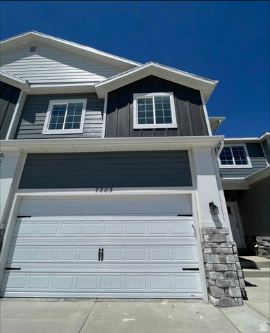 7303 North Hidden Loop Road Eagle Mountain, UT 84005 - Photo 1 of 11 Multi-level exterior with mixed siding, stone veneer accents, and a panel garage door